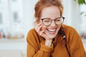 woman laughing in her kitchen relieved after her trip to the Upper Kirby TX dentist to learn about Lovett Dental Upper Kirby