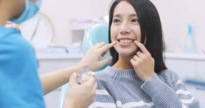 woman at the dentist pointing out her cracked tooth during cosmetic dentistry in Upper Kirby TX