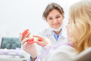 dentist showing a patient a pair of full dentures