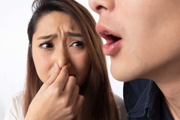 4-Causes-of-Bad-Breath a girl plugs her nose because someone has bad breath