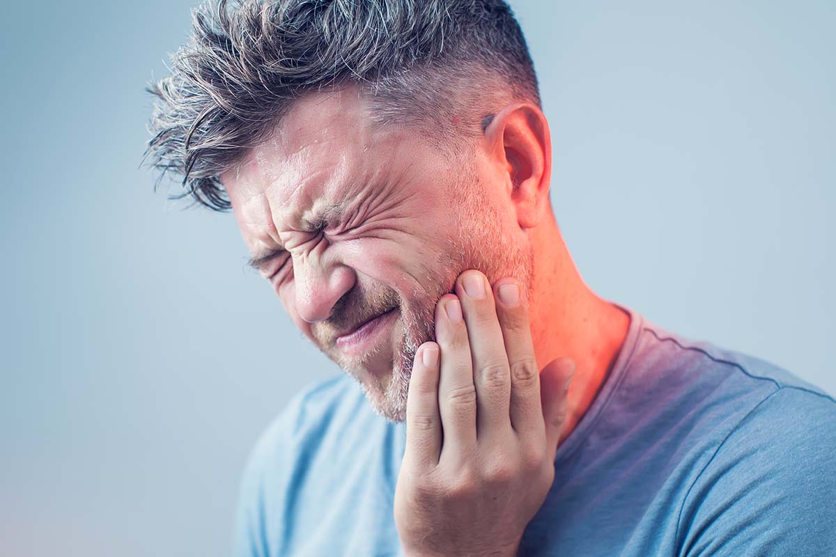 What-Is-A-Dental-Emergency a man gripes in pain as he deals with a dental emergency