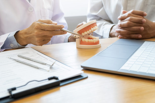 dentist pointing to figure and explaining Causes of Receding Gums