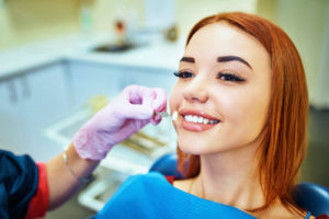 Doctor shows a woman the process of a dental bridge or crown