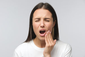 woman struggles with the pain caused by impacted teeth